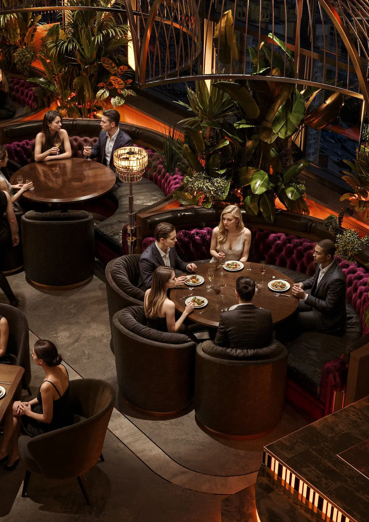 Aerial view of Zaxi Restaurant interior design in Chisinau, Moldova with round velvet booth seating, dark timber tables and lush greenery under warm ambient lighting